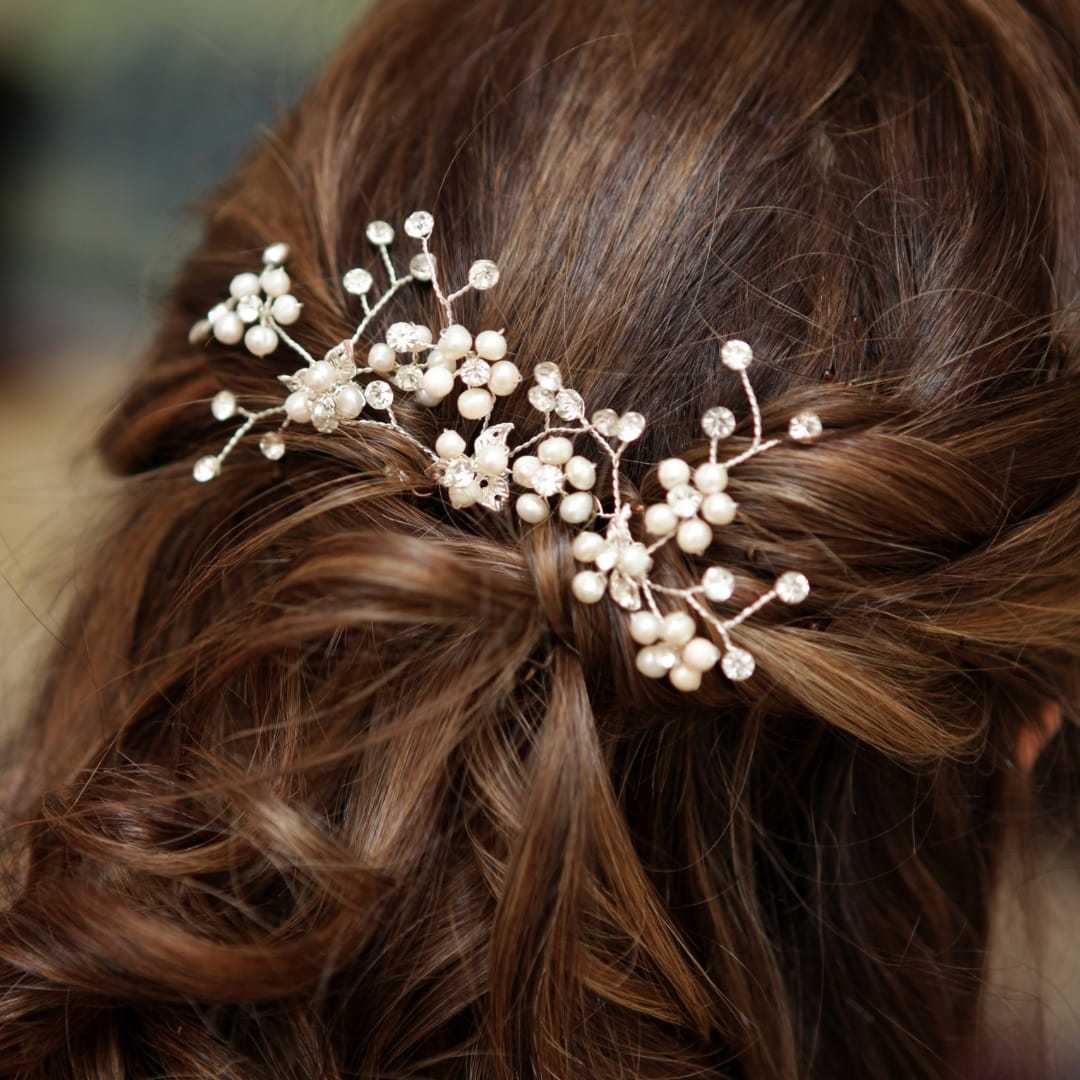 Elegant bridal hair with pearl and crystal floral accessory.